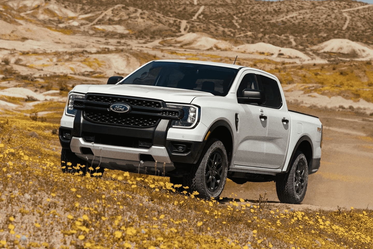 A side shot of a Gray Ford Bronco driving through the dessert.