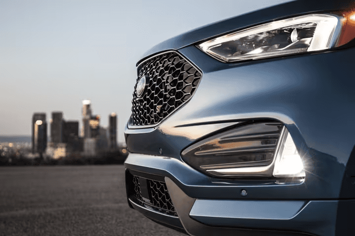 Close-up of bi-LED headlamps and fog lamps with city skyline in the background