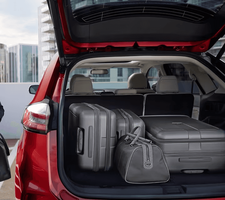 A woman beside a 2024 Ford Edge with back hatch open full of luggage