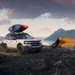 The 2026 Ford Bronco Sport with a boat on its roof rack parked near a tent
