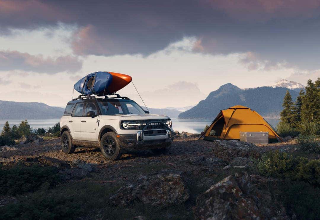 The 2026 Ford Bronco Sport with a boat on its roof rack parked near a tent