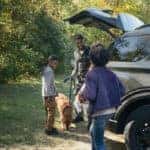 Family of three playing with their dog in front of a 2022 Ford Explorer