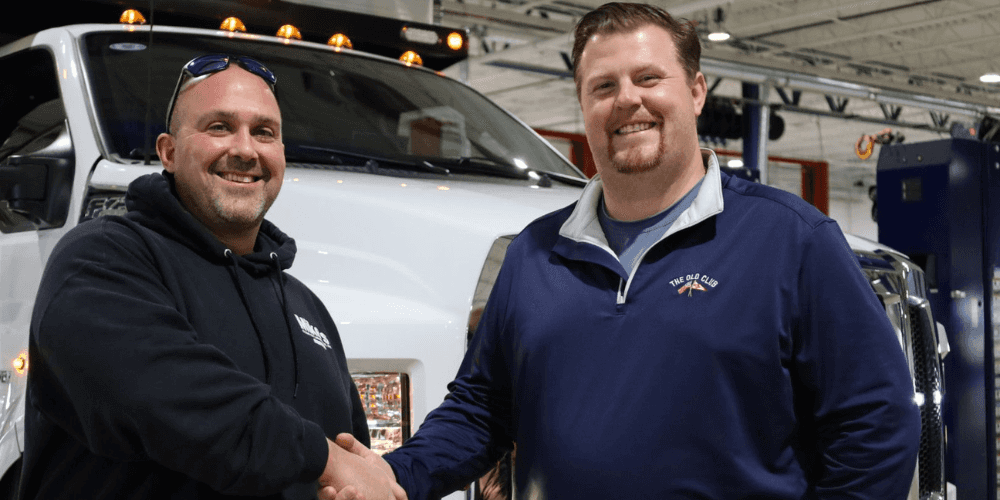 Jim from Bill Brown Ford shaking hands with a local business owner in front of their new custom 2024 Ford F-750 Super Duty in Livonia, MI