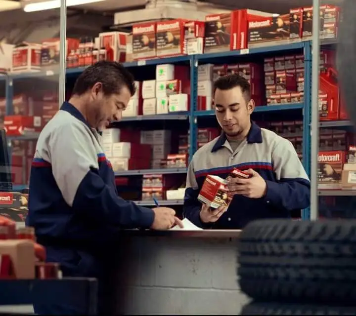 Two Parts Technicians are looking over parts in the Ford Parts Center. 