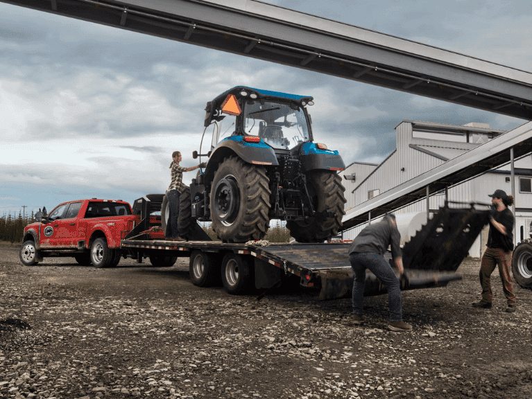 2026 Ford Super Duty® F-450® XL pickup in Race Red pulling a trailer carrying a large tractor