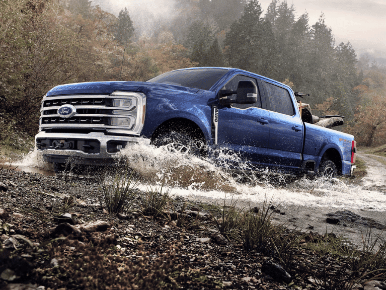 2026 Ford Super Duty® F-250® Lariat® pickup with the Tremor® Off-Road Package driving through a shallow creek