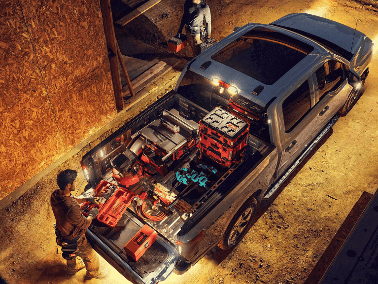 A 2025 Ford F-150® Lightning® lit up at night with a person on a construction site grabbing gear from the truck bed