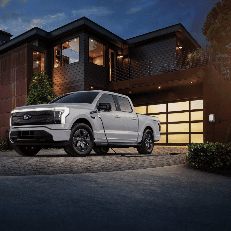 Ford F-150® Lightning® parked and charging in front of a luxury home at night