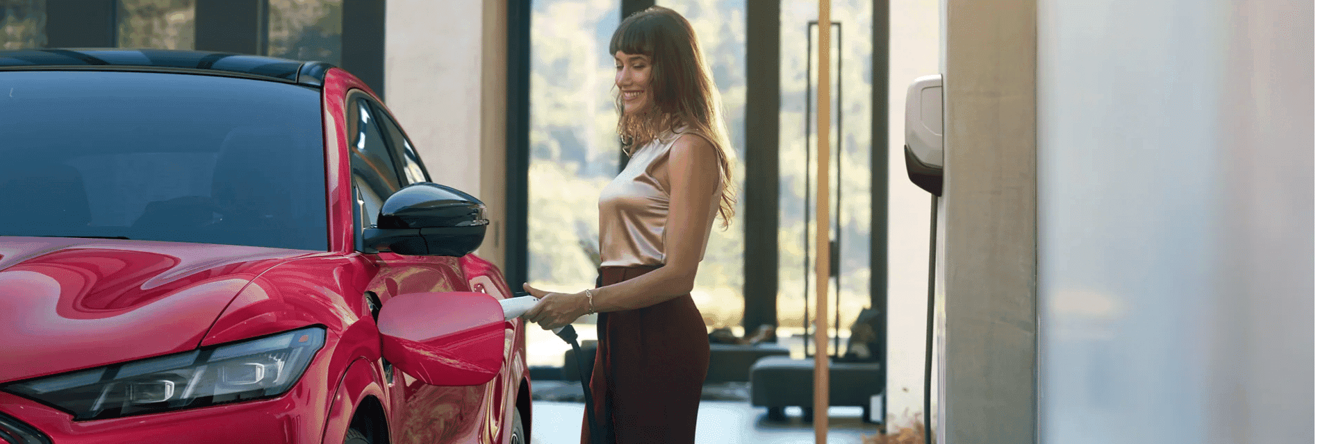 Woman plugs in a 2025 Ford Mustang Mach-E® parked outside a home