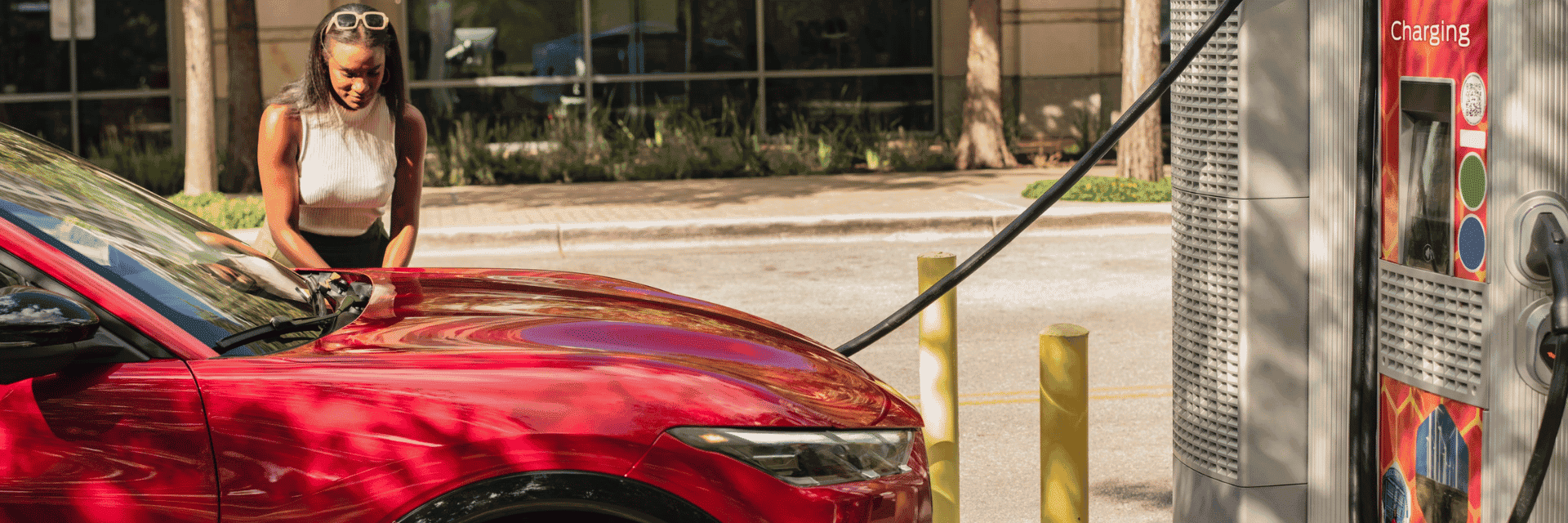 Woman plugging in a red Ford Mustang Mach-E® at a public charging station