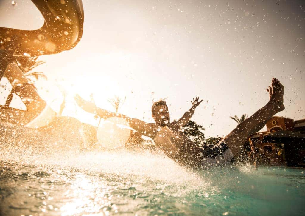 man splahsing into pool from slide at waterpark