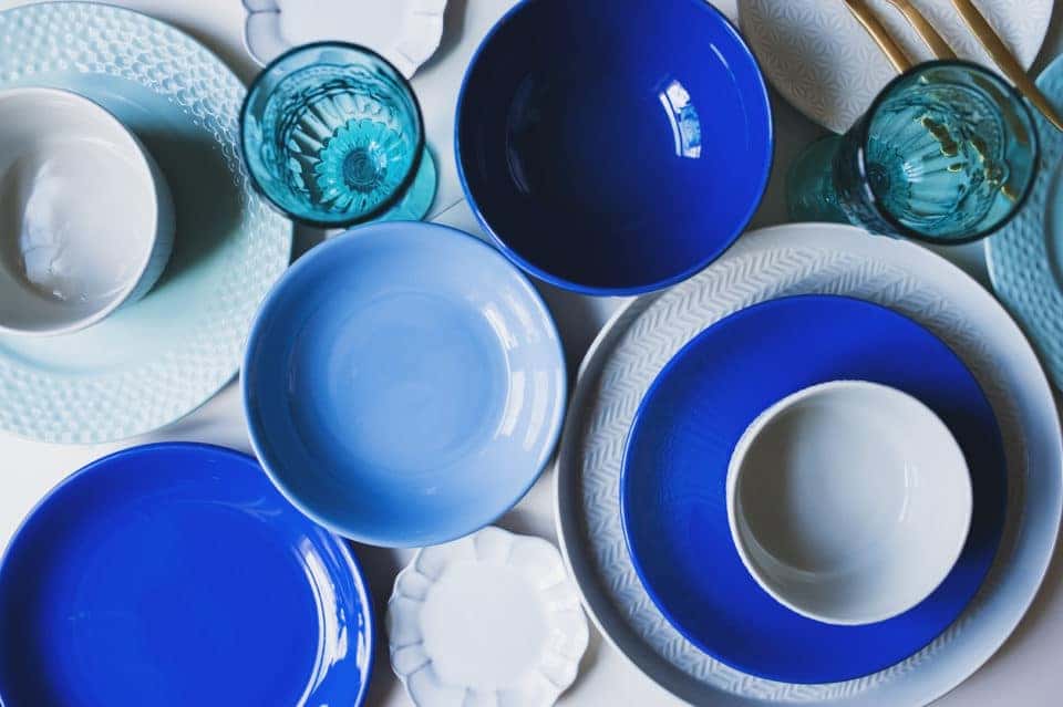 set of dishware in blue tones. Ceramic plates and water glasses top view