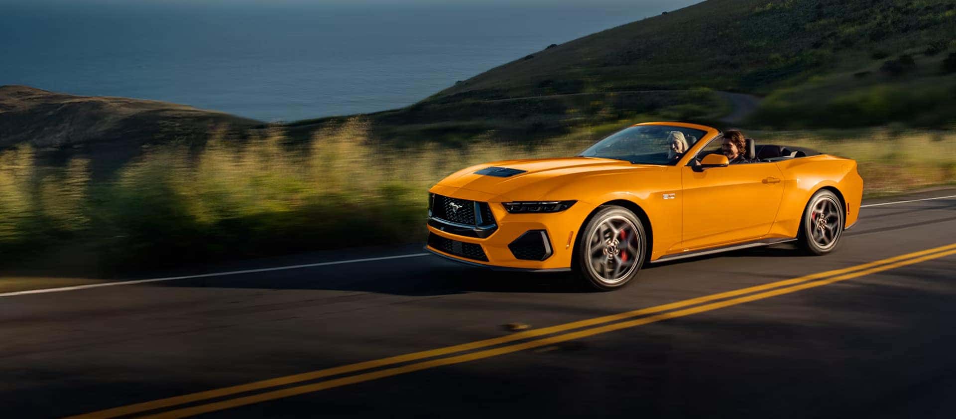 a new 2026 ford mustang driving on a road next to a filed