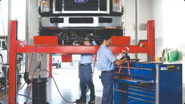 a ford vehicle loaded up into the air being worked on by ford service members