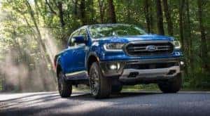 Blue 2020 Ford Ranger truck driving past green trees on a paved road
