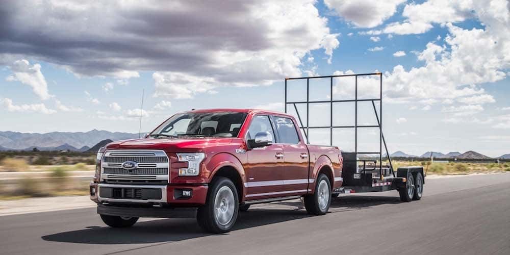 A red 2107 Ford F-150 is shown from the front at an angle while it tows a trailer.