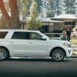 White 2018 Ford Expedition SUV parked in front of a stone house with a couple on the walkway