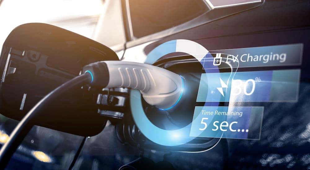 An electric car is shown charging with a closeup on the plug.