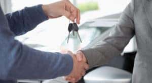 Two hands are shaking inside a Ford Dealership near Troy, NY, while one of the hands is holding car keys.