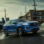 Blue 2019 Ford Edge SUV parked in the middle of an intersection surrounded by buildings and traffic lights