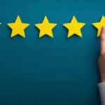 Person's hand pressing a fifth yellow star against a blue wall