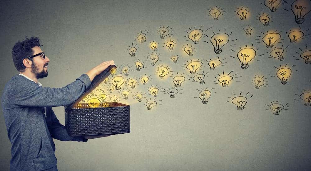 Man in a blue sweater holding a basket open with cartoon lightbulbs coming out of it close to a Ford dealership near you.