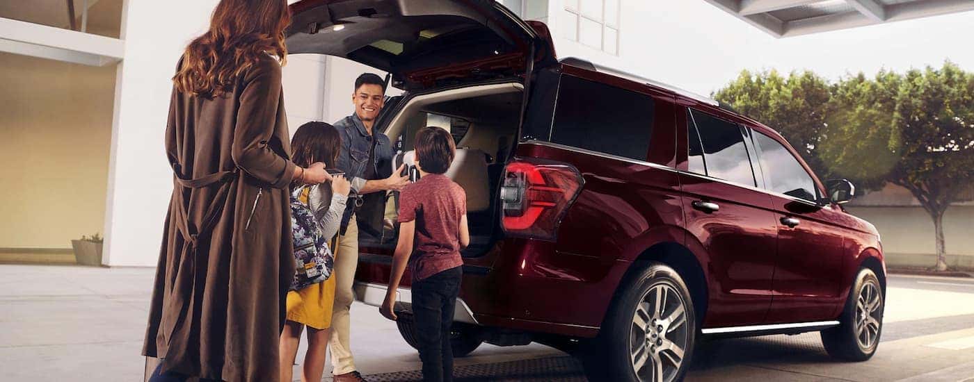 A family is shown around the rear cargo area of a red 2023 Ford Expedition Limited.