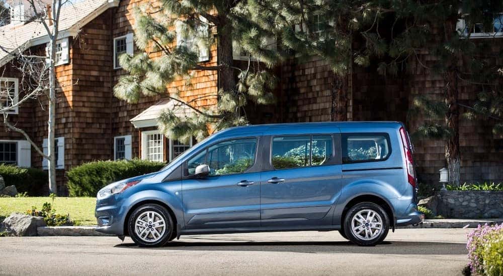 Blue 2019 Transit Connect parked in front of a brown house with a green lawn