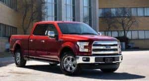 Red used Ford truck parked outside of a brick building after the owner searched used trucks for sale.
