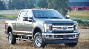 Used Ford heavy duty truck parked in a field with a red barn in the background