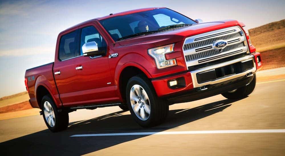 A red 2015 Ford F150 is shown driving down the highway at speed.