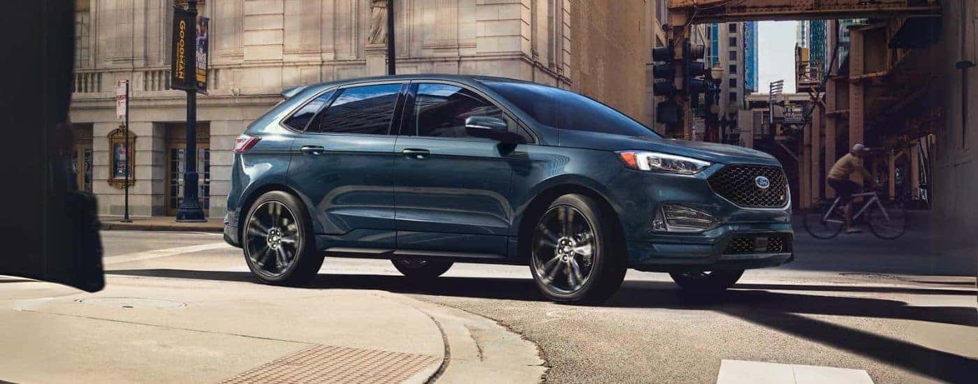 A blue 2022 Ford Edge Titanium is shown rounding a corner on a city street.