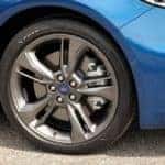 Closeup of a black Goodyear tire with a chrome Ford rim on a blue 2017 Ford Fusion Sport