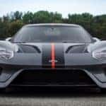 Gray 2019 Ford GT Carbon Series with a back and red racing stripe in the middle of the hood parked on a race track in front of a tree line