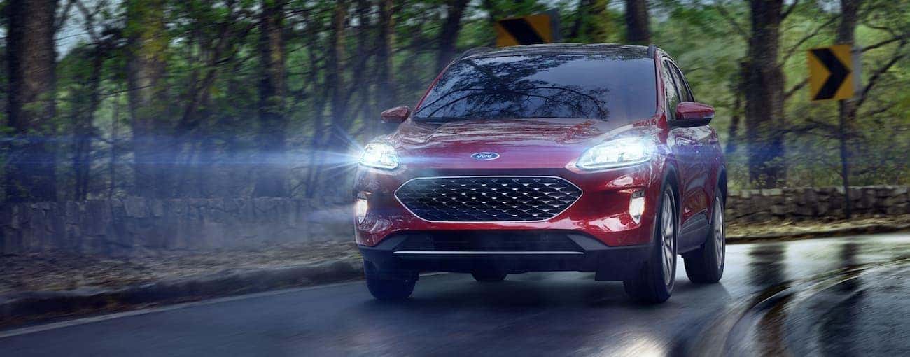 A red 2020 Ford Escape is driving in the rain in Albany, NY.