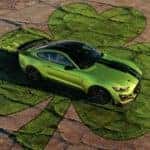 Lime green 2020 Mustang parked on top of a green clover painted on stone