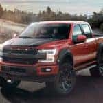 A red lifted 2019 Ford F-150 SC, a popular option at local car dealers, is parked next to a grassy field.