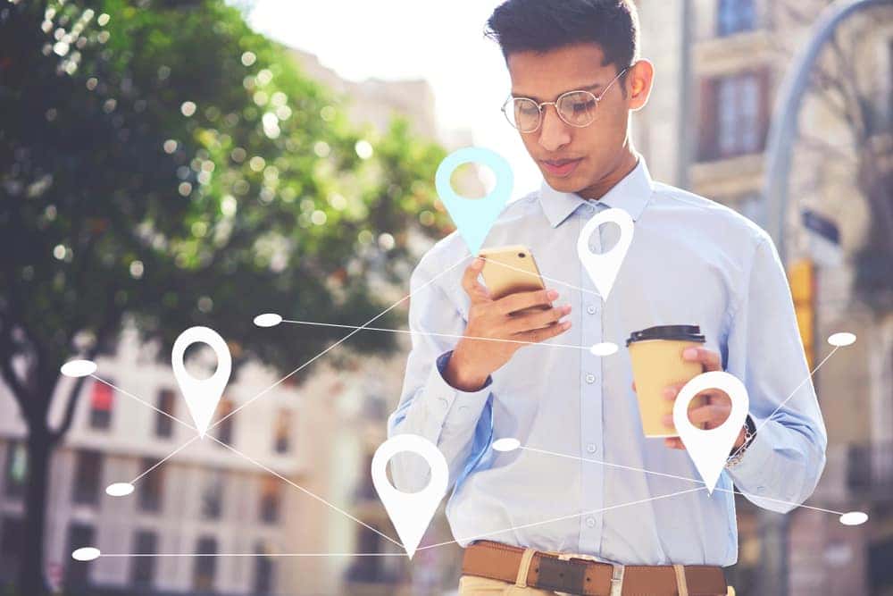 A man walking down the street on his phone looking for a Ford Dealership Near Me