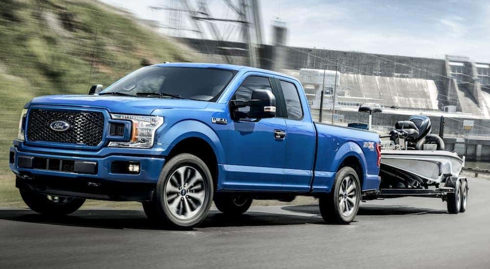 A blue 2020 Ford F-150, a popular truck at local Ford dealership locations in Albany, NY, is towing a boat.