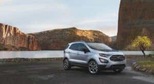One of the most popular Ford SUVs, a silver 2020 Ford EcoSport, is shown in front of a lake.