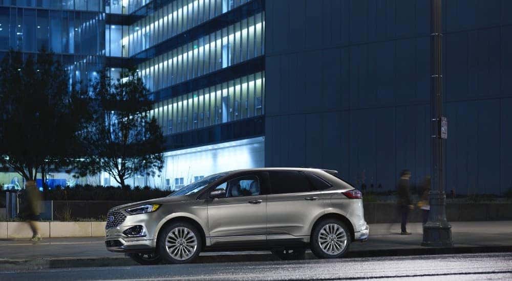 Silver 2020 Ford Edge parked on the street in front of a glass office building with blue lights in the windows after the owner searched ''used SUVs for sale''.