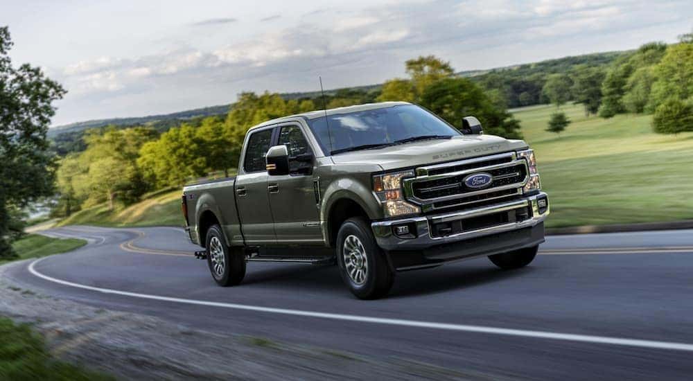 A green 2020 Ford F-250 is shown from the front at an angle driving down the road.