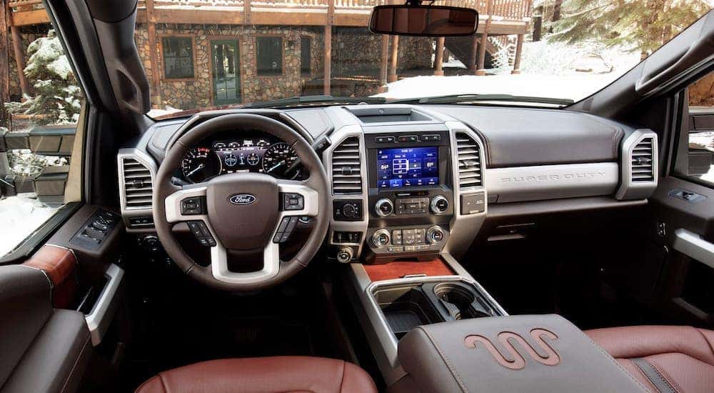 The interior and front seat of a 2020 Ford Super Duty overlooking a winter cabin.