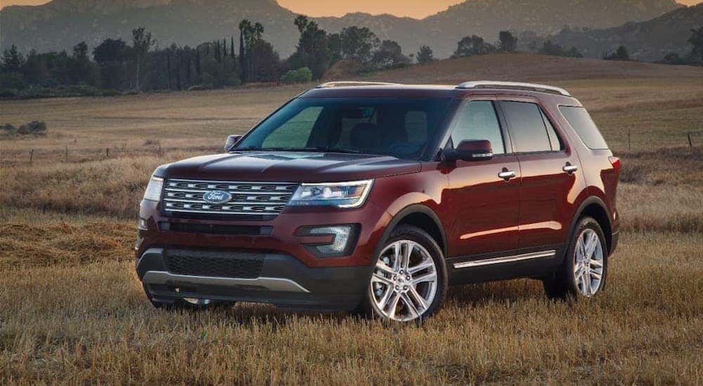 A red 2016 Ford Explorer is parked in a field in front of mountains.