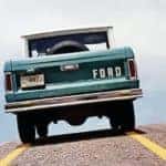 A green 1966 Ford Bronco is shown from the rear on a highway.