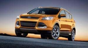 A orange used 2016 Ford Escape is shown from a low angle at sunset.