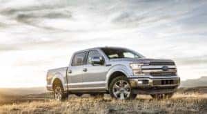 A popular used Ford F-150, a silver 2018 Ford F-150, is shown parked in tall grass.