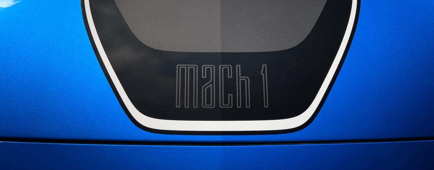 A top-down view shows the Mach 1 badging on the hood of a blue 2021 Ford Mustang Mach 1.