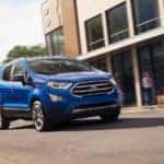 A blue 2019 used Ford EcoSport is driving on a city street near Albany, NY.