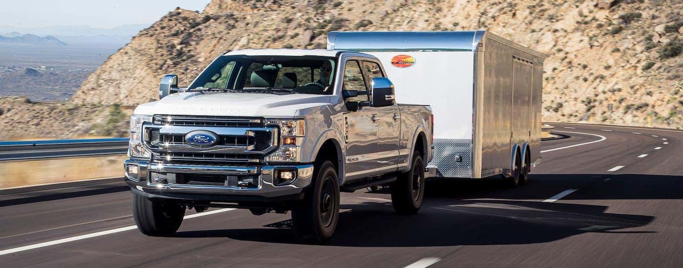 A white 2021 Ford F-350 diesel is towing a white enclosed trailer.